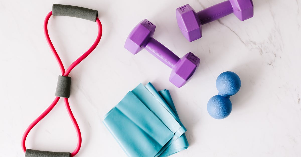 Colorful home workout equipment, including dumbbells and resistance bands, on a marble surface.